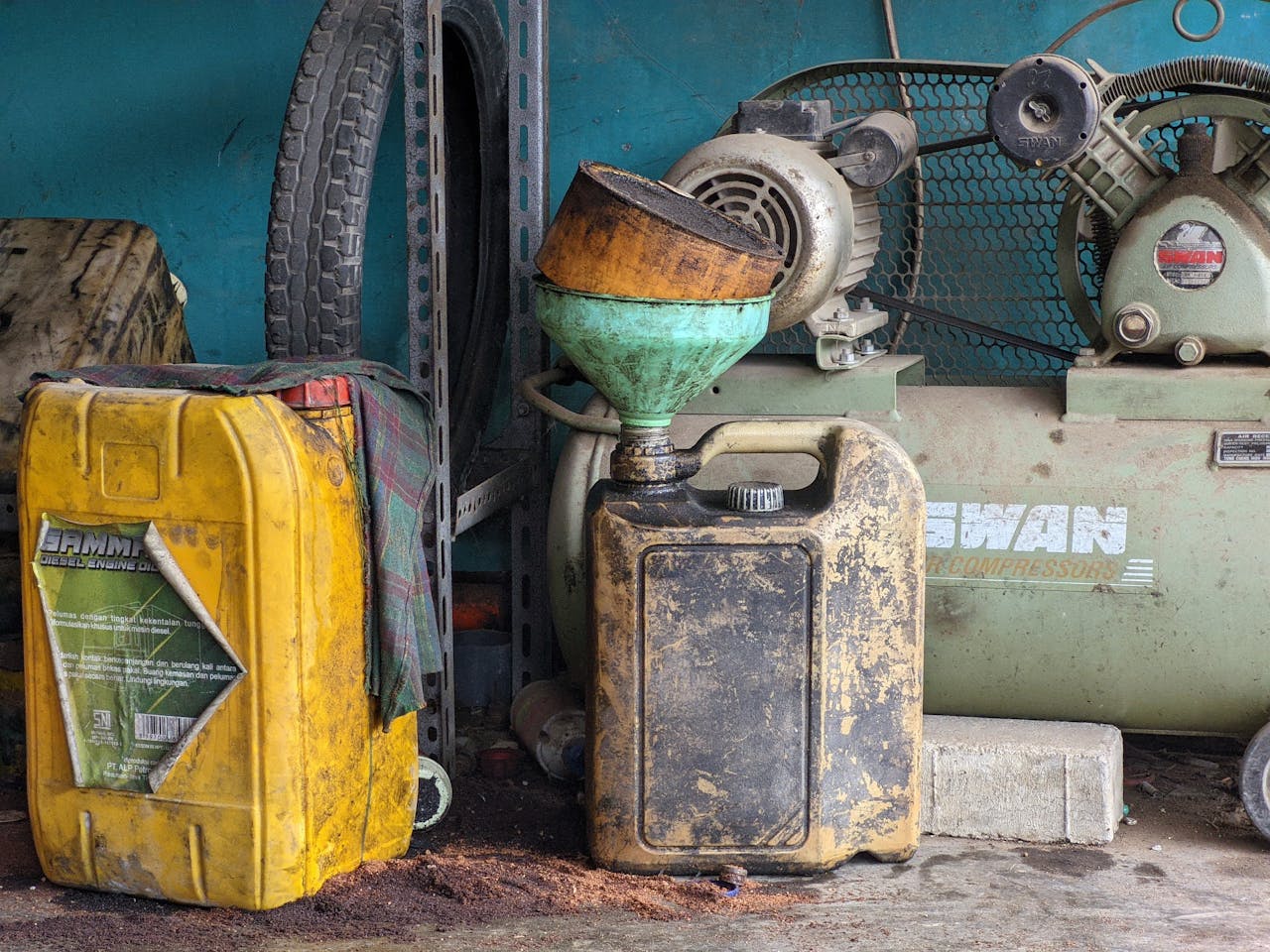 A worn metal drum and vintage compressor in an industrial workshop setting, exuding a classic and rustic feel.