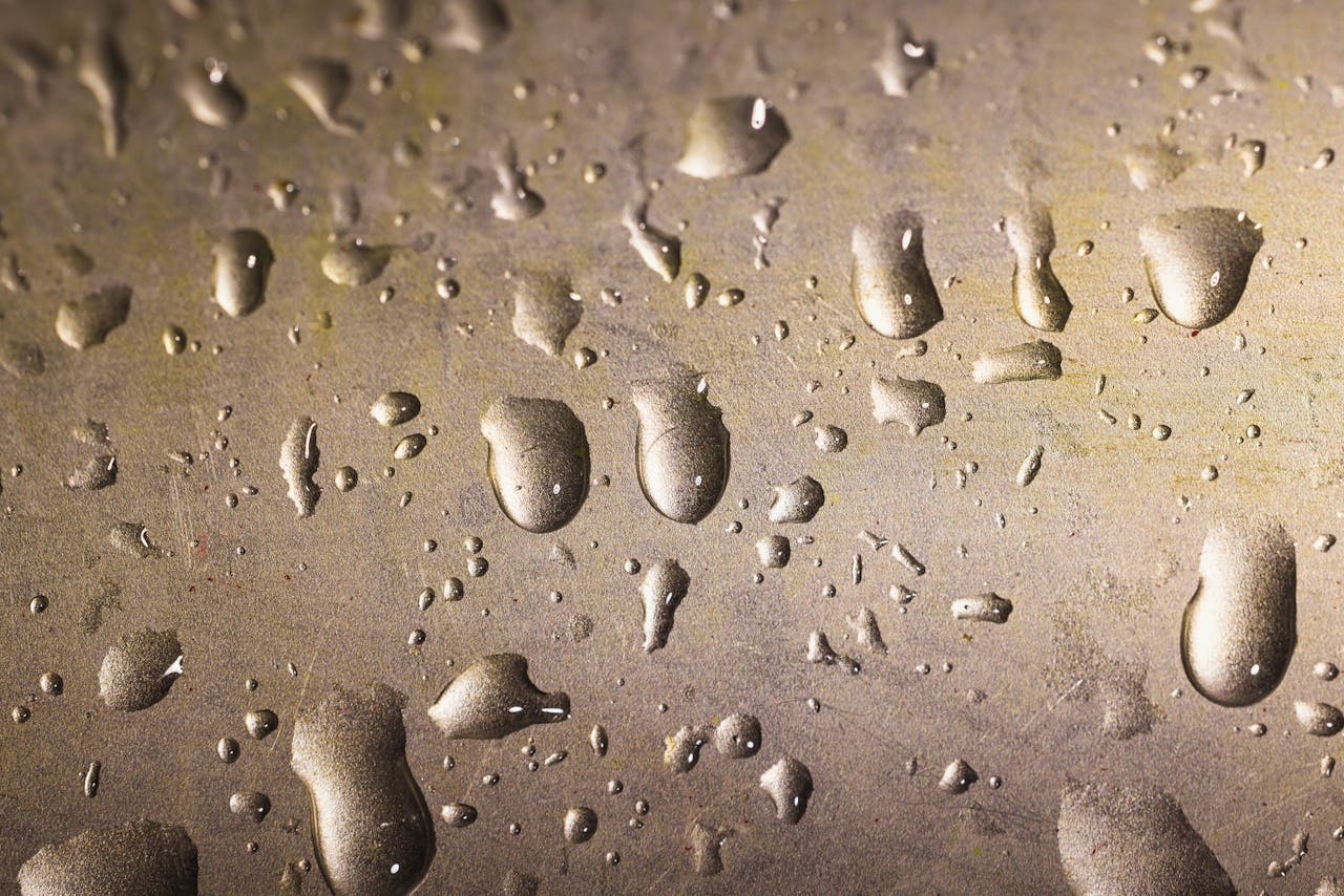Close-up of water droplets on a textured metallic surface, creating a modern abstract pattern.